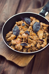 Roasted pork with basil leaves in a frying pan, vertical shot