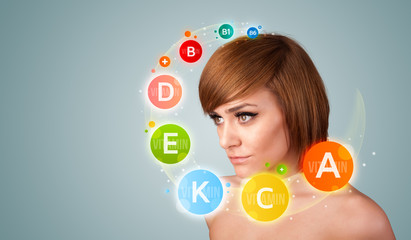 Pretty young girl with colorful vitamin icons and symbols