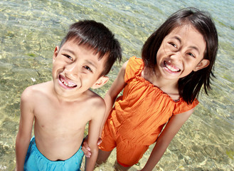 Close up portrait of happy asian kids in the beach smiling