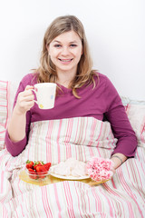 Happy woman enjoying breakfast in bed