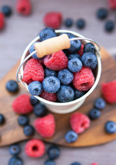 Fresh blueberries and raspberries in a  bucket