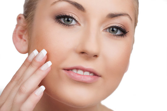 Skin care. Close-up of cheerful woman looking at camera and touc