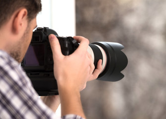 Fototapeta na wymiar Photographer. Young man photographing something outside the wind