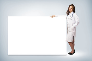 young woman doctor standing near a blank banner