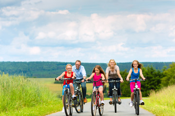 Family cycling in summer in rural landscape