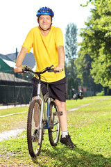 Obraz premium Full length portrait of a mature man in sportswear on his bike
