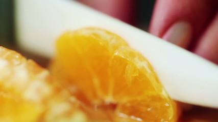 Closeup of woman hands slicing lime tangerine