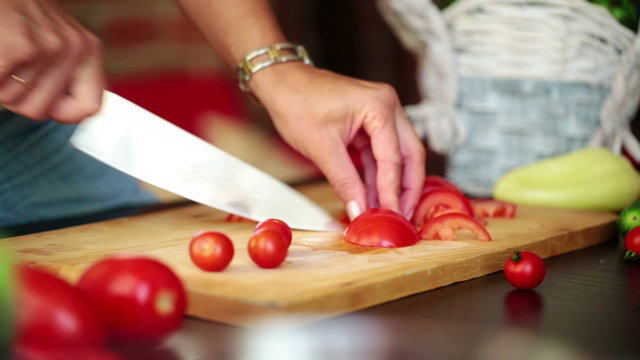 Woman hands slicing tomato in kitchen