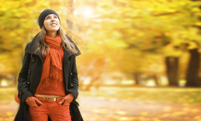 A young brunette woman in warm clothes in an autumn park