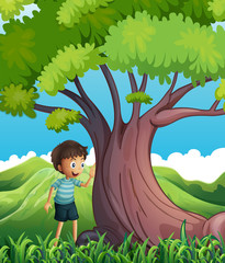 A young boy beside the huge tree