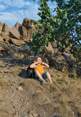 Playful little boy sitting waiting on a mountain