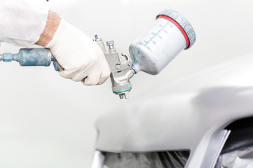 close-up of a spray paint gun, painting a car