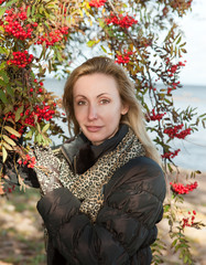 The young woman near red berries of a ripe mountain ash...