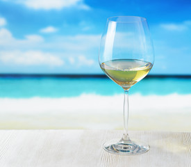 Glass of wine on beach background