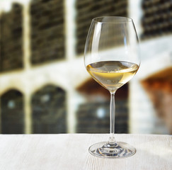 Glass of wine and wooden barrels in winery