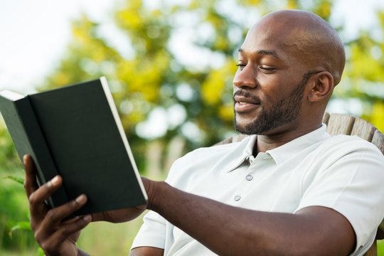 Handsome Black Man Reading Book at Park