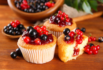 Tasty muffins with berries on wooden table