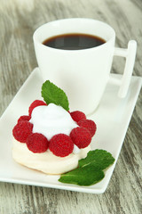 Tasty meringue cake with berries and cup of coffee,