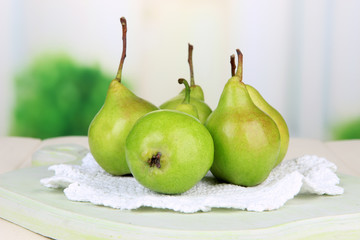 Pears on wooden cutting board, on light background