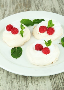 Tasty meringue cakes with berries on wooden table