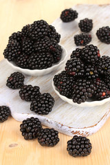 Sweet blackberry in bowls on wooden table