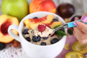 Oatmeal in cup with berries on napkins on wooden table