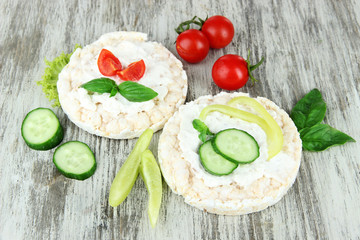 Tasty crispbreads with vegetables on wooden background