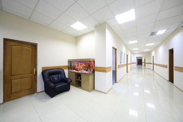 Fototapeta na wymiar Light white corridorswith doors to offices and aquarium