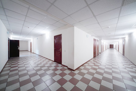 Two long hallways with brown wooden doors and floor