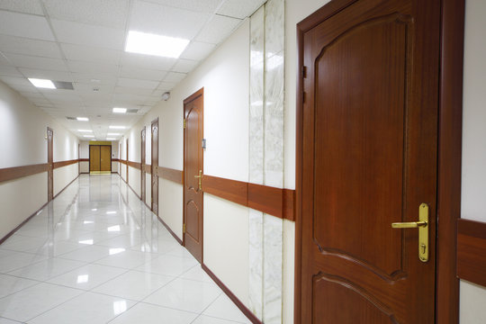 Long light hallway with brown wooden doors
