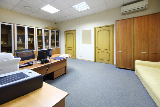 Empty working area with desktop, bookcase and sofa in office