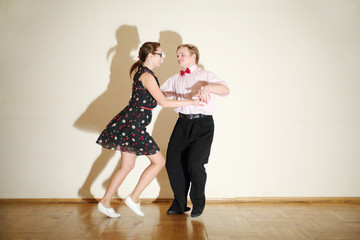 Young happy man and woman in dress dance at boogie-woogie party.