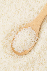 Uncooked white rice on wooden spoon