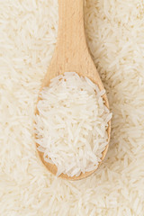 Uncooked white rice on wooden teaspoon