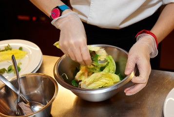 Chef is mixing salad at professional kitchen