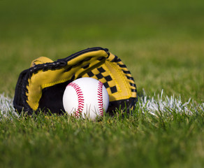 Baseball in yellow glove on field with yard line and grass