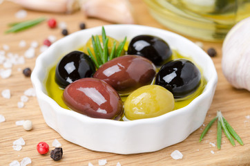 close-up of a bowl with different olives in olive oil and spices