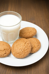 glass of milk and oat cookies on a plate, close-up