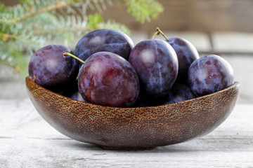 Wooden bowl of plums