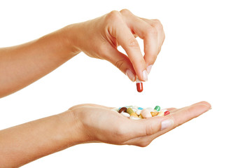 Hand hält Pille über Medikamenten