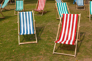 Canvas deckchairs on a grassy lawn in the summer.