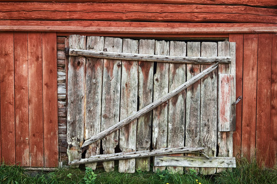 Wooden door on an old red painted weathered barn.