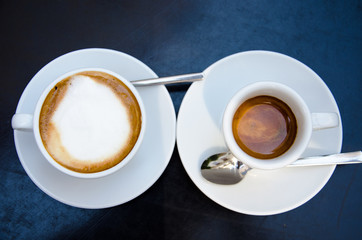 Top view of white macciato and espresso cup on the black table