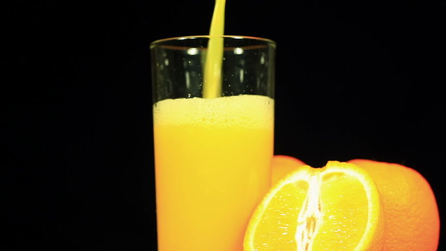 Orange juice is poured in a glass on a black background