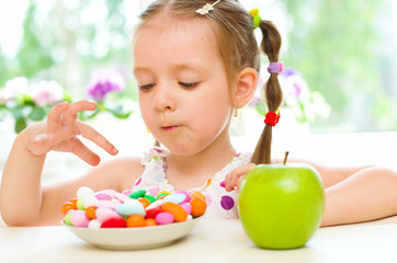 child choosing between apple and sweets