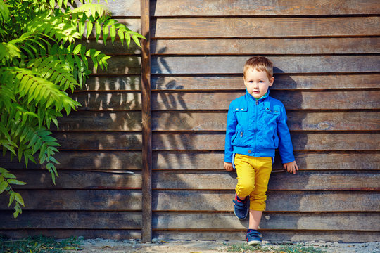 portrait of cute fashionable boy in front of wooden wall