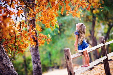 Pretty little girl relax on beauty autumn landscape background