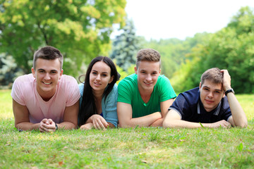 Fototapeta premium czterech uśmiechniętych studentów studiujących w zielonym parku