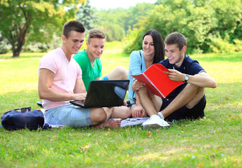 Fototapeta na wymiar four smiling student studying in green park