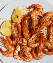 Hot grilled black tiger prawns on white plate with lemon